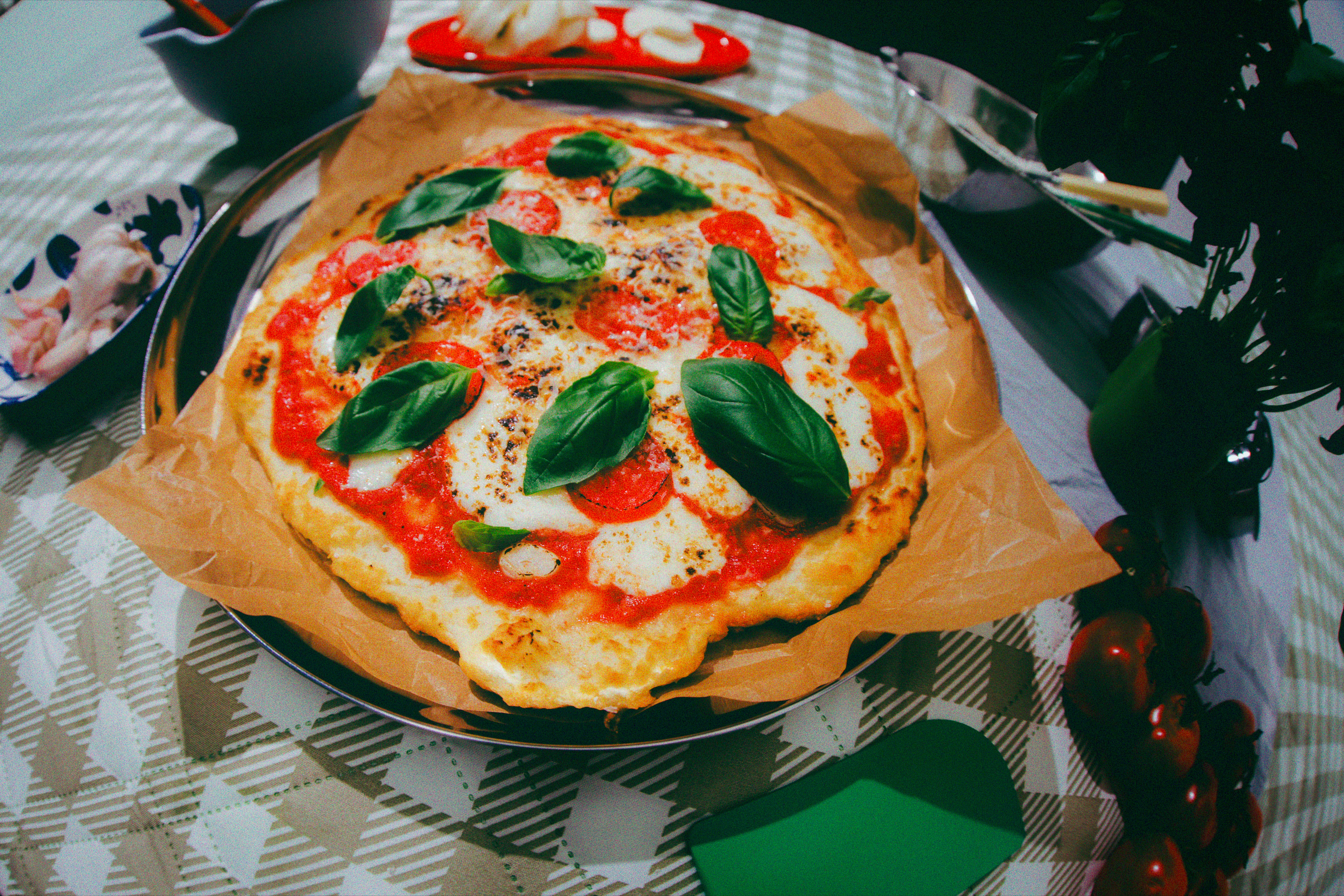 Margherita pizza topped with basil on parchment paper